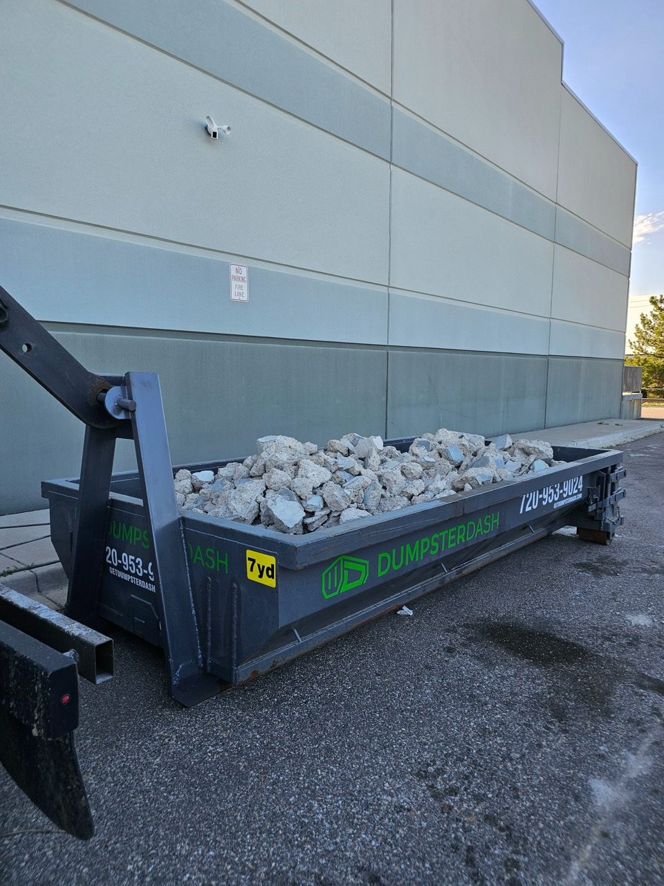 Large concrete slab pieces loaded into a bin on a residential street